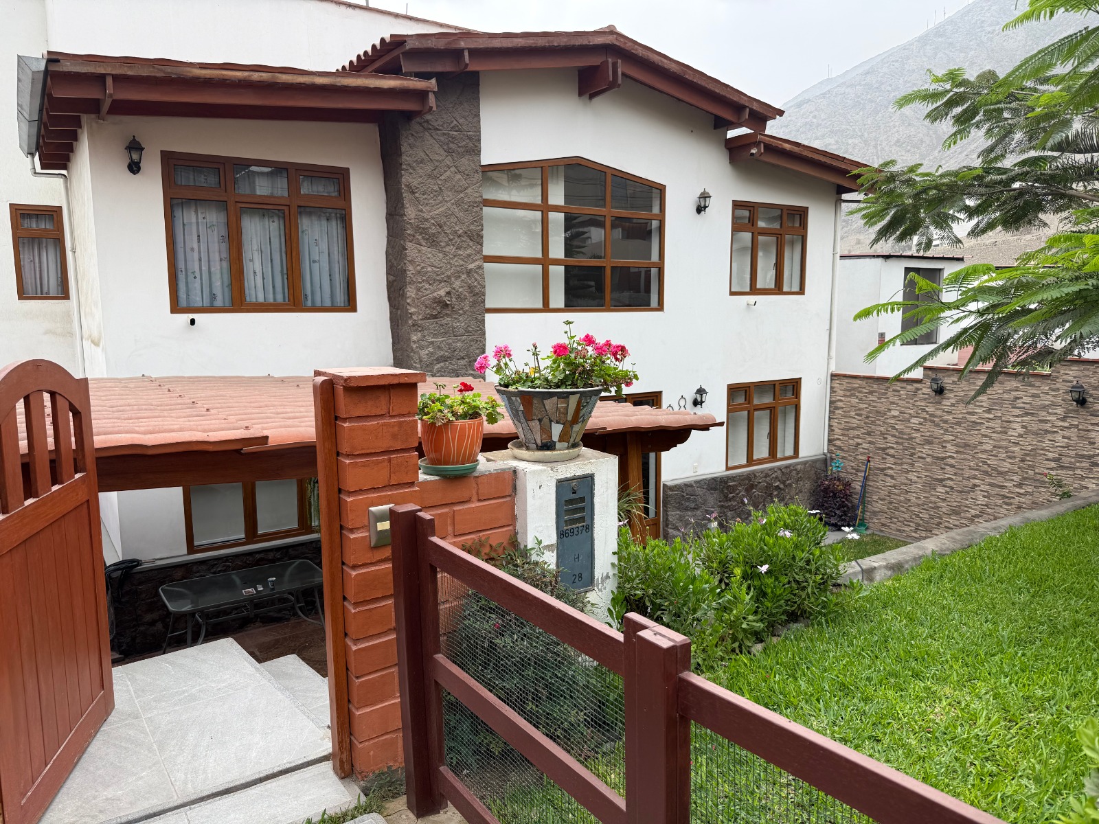 Fachada real de la casa El Cuadro, con ventanas de madera, jardín y vista a las montañas